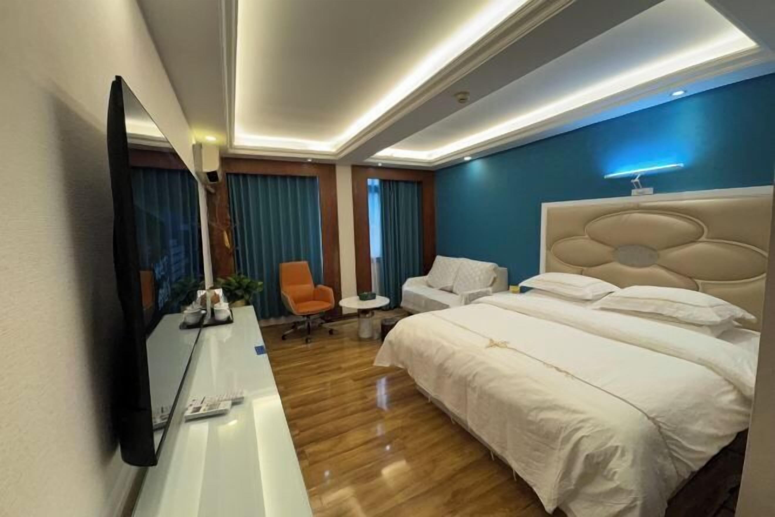 A hotel room with a large bed, a desk with a mirror, a chair, and a small table.