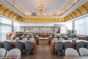 A conference room with tables and chairs arranged for meetings, a large chandelier, and a view of the city through large windows. - Feicui Hotel (Mangshi)
