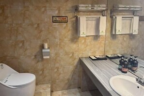 Casa de banho com sanita, lavatório e toalheiro com toalhas.