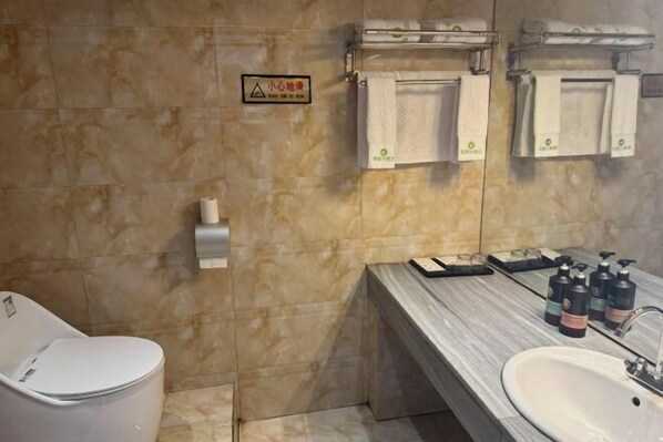 Un baño con inodoro, lavamanos y toallero con toallas.