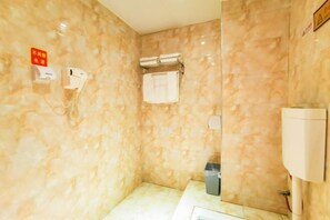 Un baño con paredes de mármol, un perchero, un teléfono y un calentador de agua.