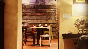 A cozy dining area with a rustic stone wall, wooden ceiling, and a table set for two. - River Rock Inn B&B - Adults Only (Green River)
