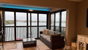 Ein Balkon mit Blick auf ein Gewässer, eine Couch, ein Couchtisch und ein Schrank.