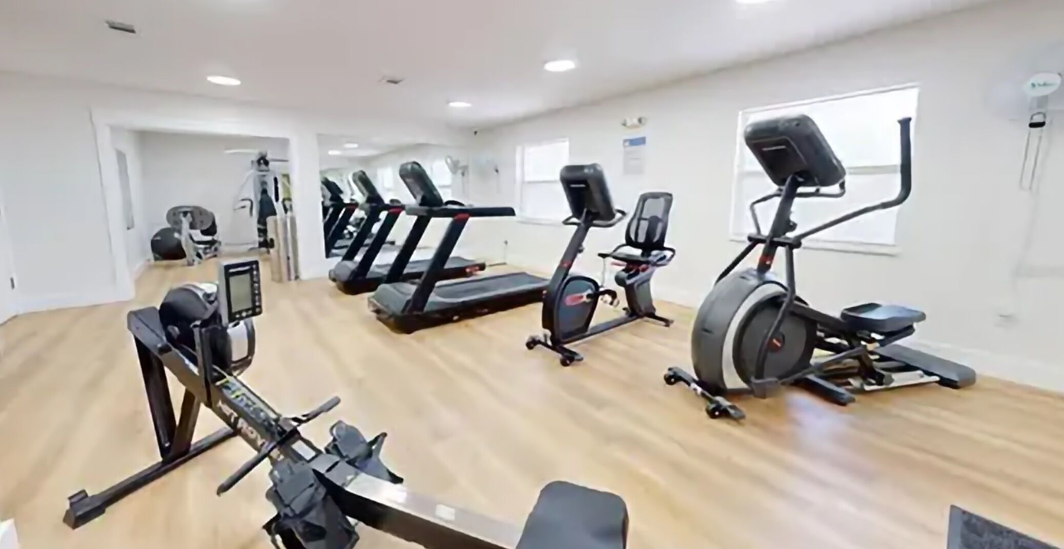 A gym with treadmills, stationary bikes, and a rowing machine.