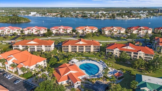 Ein Resort mit mehreren Gebäuden, einem zentralen Schwimmbad und einem Yachthafen im Hintergrund.