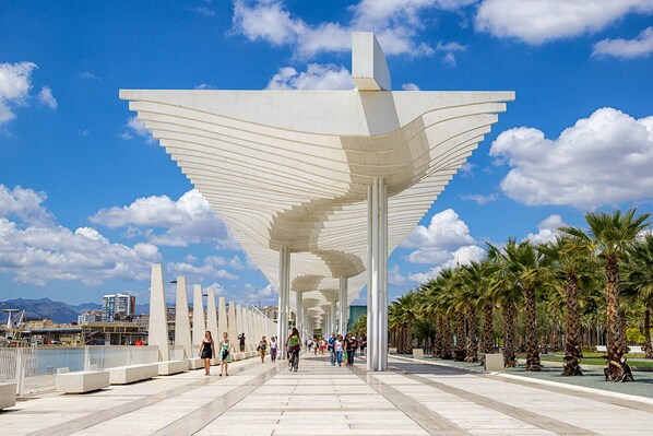 Une structure architecturale moderne, caractérisée par une série de colonnes blanches et incurvées, ainsi qu’une vaste auvent blanc en forme de parapluie.