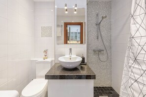 Une salle de bain moderne avec un lavabo blanc, des toilettes et une douche.