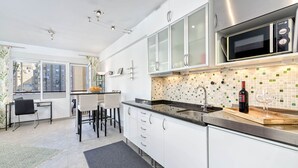 Una cocina moderna con gabinetes blancos, un microondas de acero inoxidable y un salpicadero de azulejos.