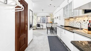 Una cocina moderna con armarios blancos, encimera de granito y salpicadero de azulejos.