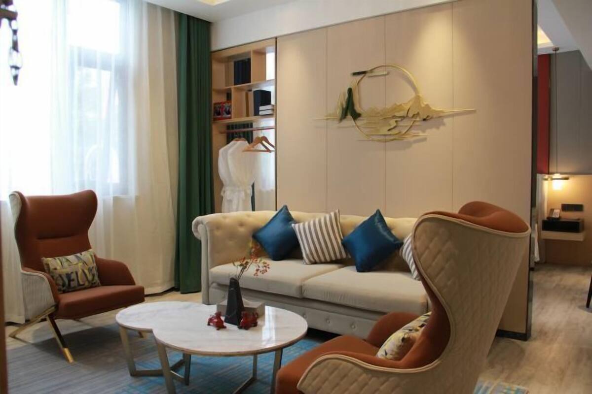 Una sala de estar moderna con un sofá color beige, dos sillones, una mesa de centro y una estantería.
