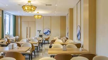 A restaurant with tables and chairs arranged in a spacious layout, overhead lighting fixtures, and artwork on the walls.