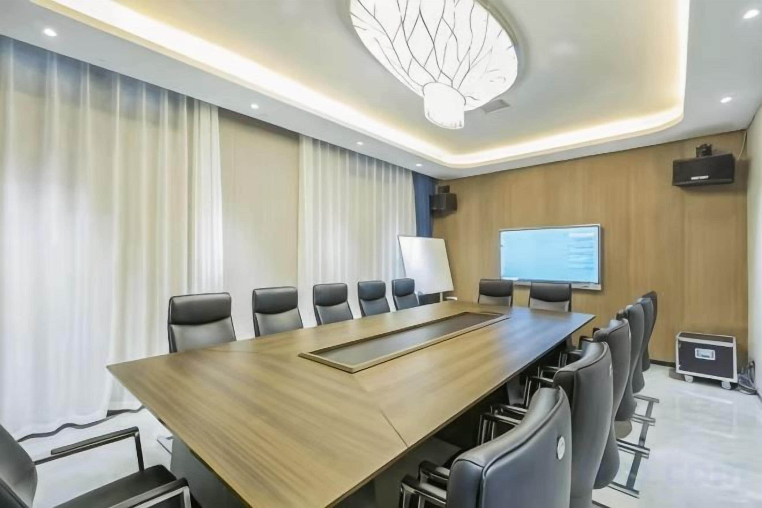 A conference room with a long table, chairs, a projector screen, and a whiteboard.