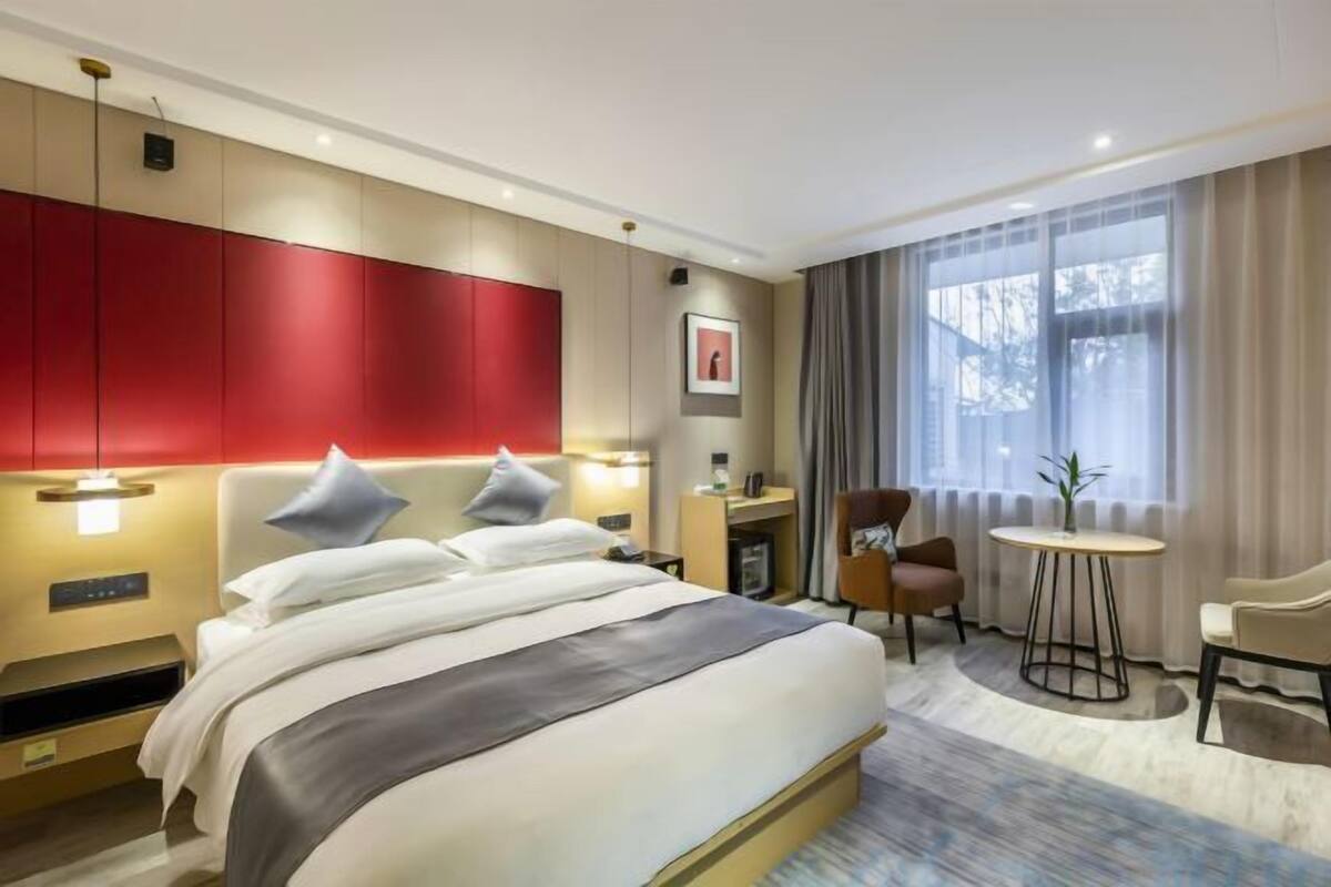 Una habitación de hotel con una cama grande, un escritorio, una silla y una mesa redonda.