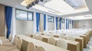 Un salón de conferencias con filas de mesas y sillas, ventanas amplias y un diseño moderno del techo.
