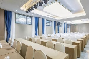 Un salón de conferencias con filas de mesas y sillas, ventanas amplias y un diseño moderno del techo.