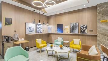 A modern hotel lobby with a reception desk, seating area, and artwork on the walls.