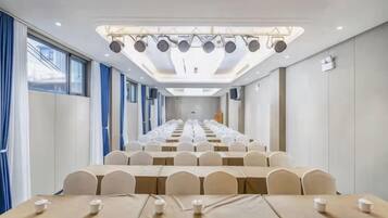 A conference room with rows of tables and chairs, a long table with a tablecloth, and a ceiling with lights.