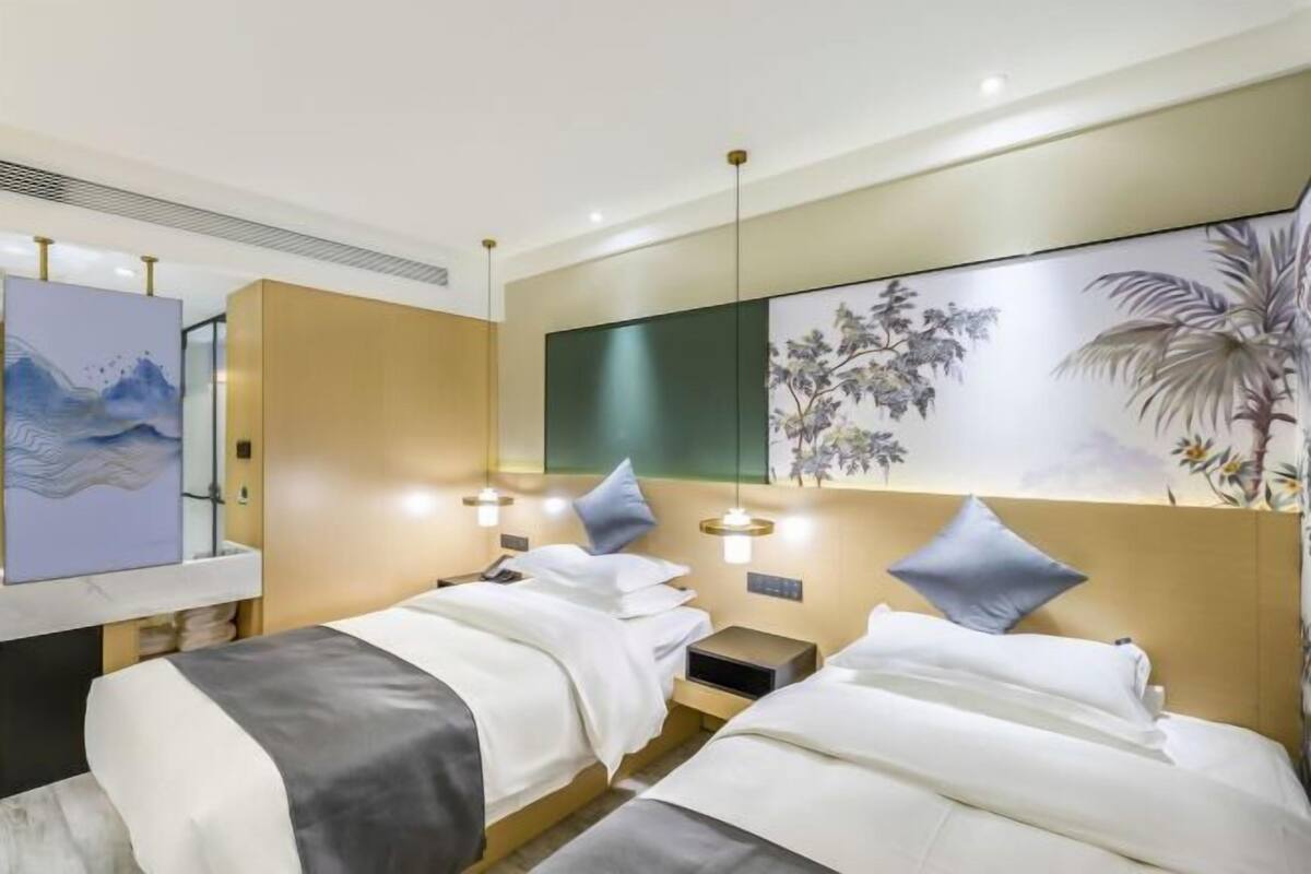 Habitación de hotel con dos camas, un espejo grande, decoración en la pared y lámparas de noche.