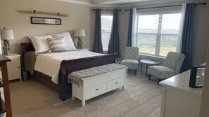 A bedroom with a bed, bedside tables, a bench, a chair, and a small table.