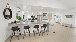 Une cuisine spacieuse dotée d’un îlot central, de tabourets de bar et d’un grand miroir.