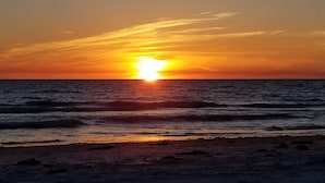 Una puesta de sol sobre el océano con olas acercándose a la orilla.