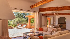 A spacious living area with a sofa set, a coffee table, and a view of an outdoor patio with lounge chairs. - Villa Domaine de Pinarello (Pinarello)