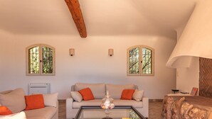 A spacious living room with a sofa, a coffee table, and a fireplace. - Villa Domaine de Pinarello (Pinarello)
