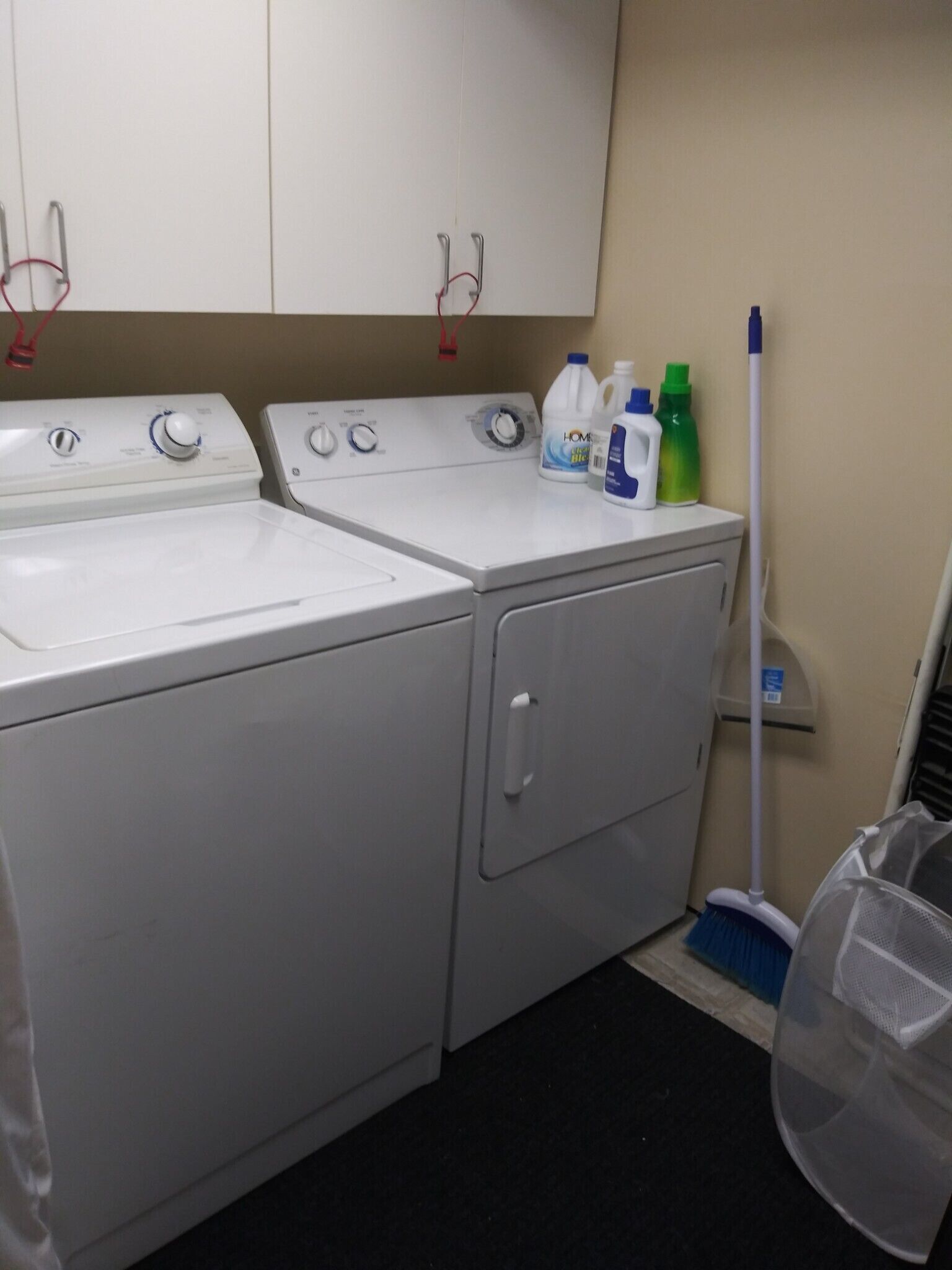 A laundry area with two washing machines, a drying rack, and cleaning supplies.