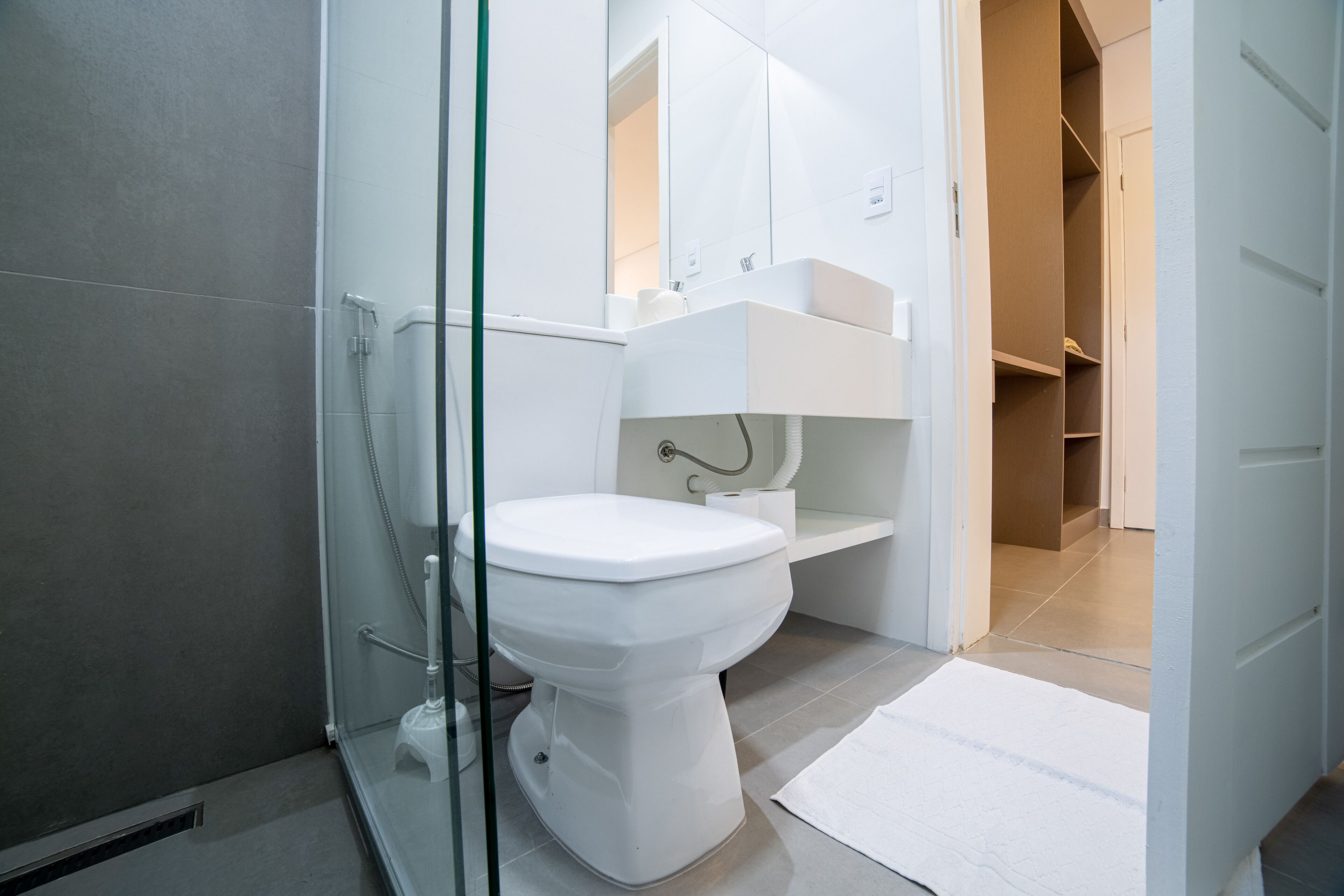 Une salle de bain moderne dotée d’une douche à parois de verre, de toilettes blanches et d’un lavabo intégré avec un porte-serviettes.