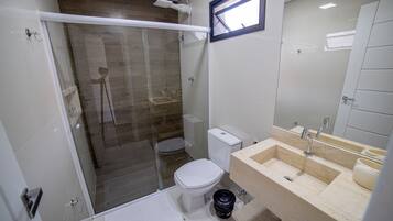 Un baño moderno con ducha acristalada, inodoro y lavamanos con espejo.