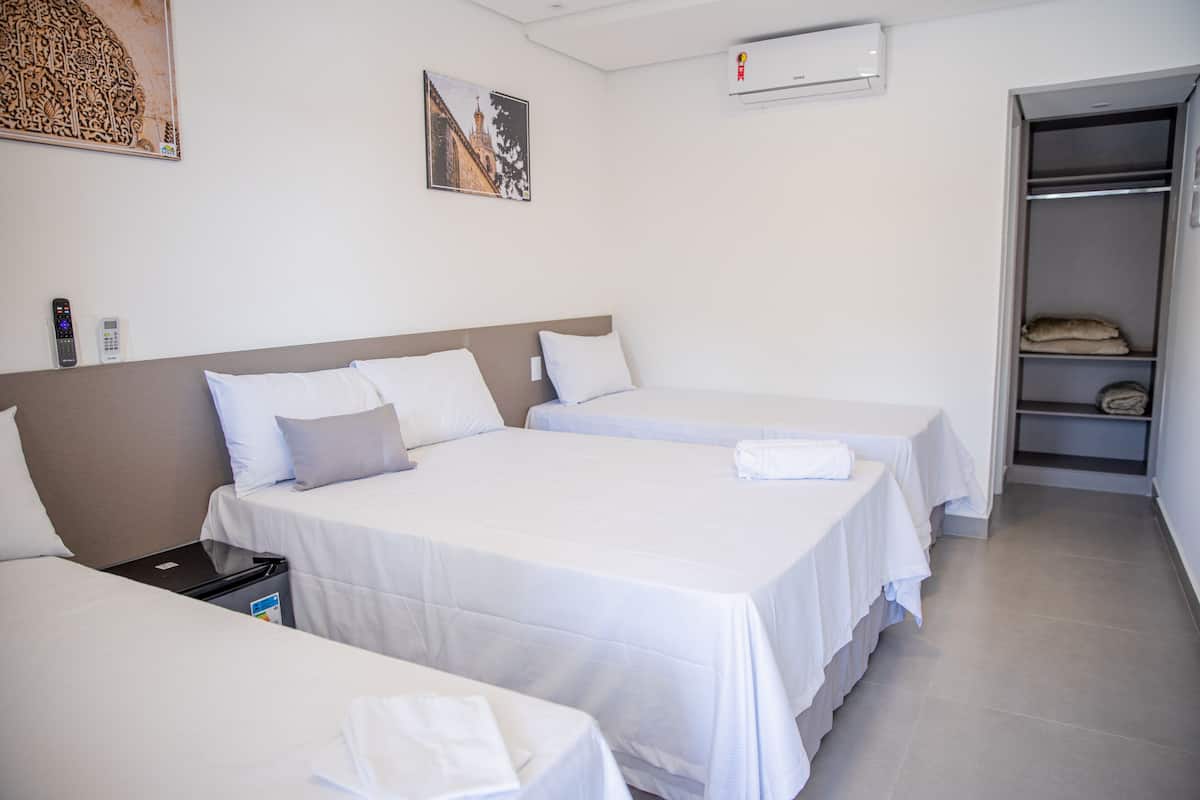 A hotel room with two single beds, a wardrobe, and a small table with a remote control and a phone.