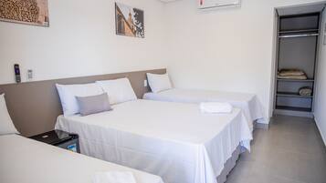 A hotel room with two single beds, a wardrobe, and a small table with a remote control and a phone.