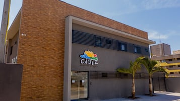A building with a sign reading "CADIZ POUSA DA ELAZER" and two palm trees in front.