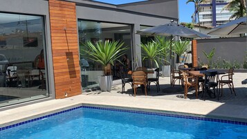 Una piscina al aire libre, sillones reclinables de piscina