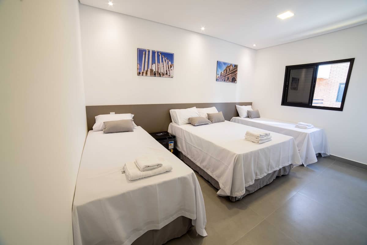 A hotel room with two single beds, a small table, and a window.