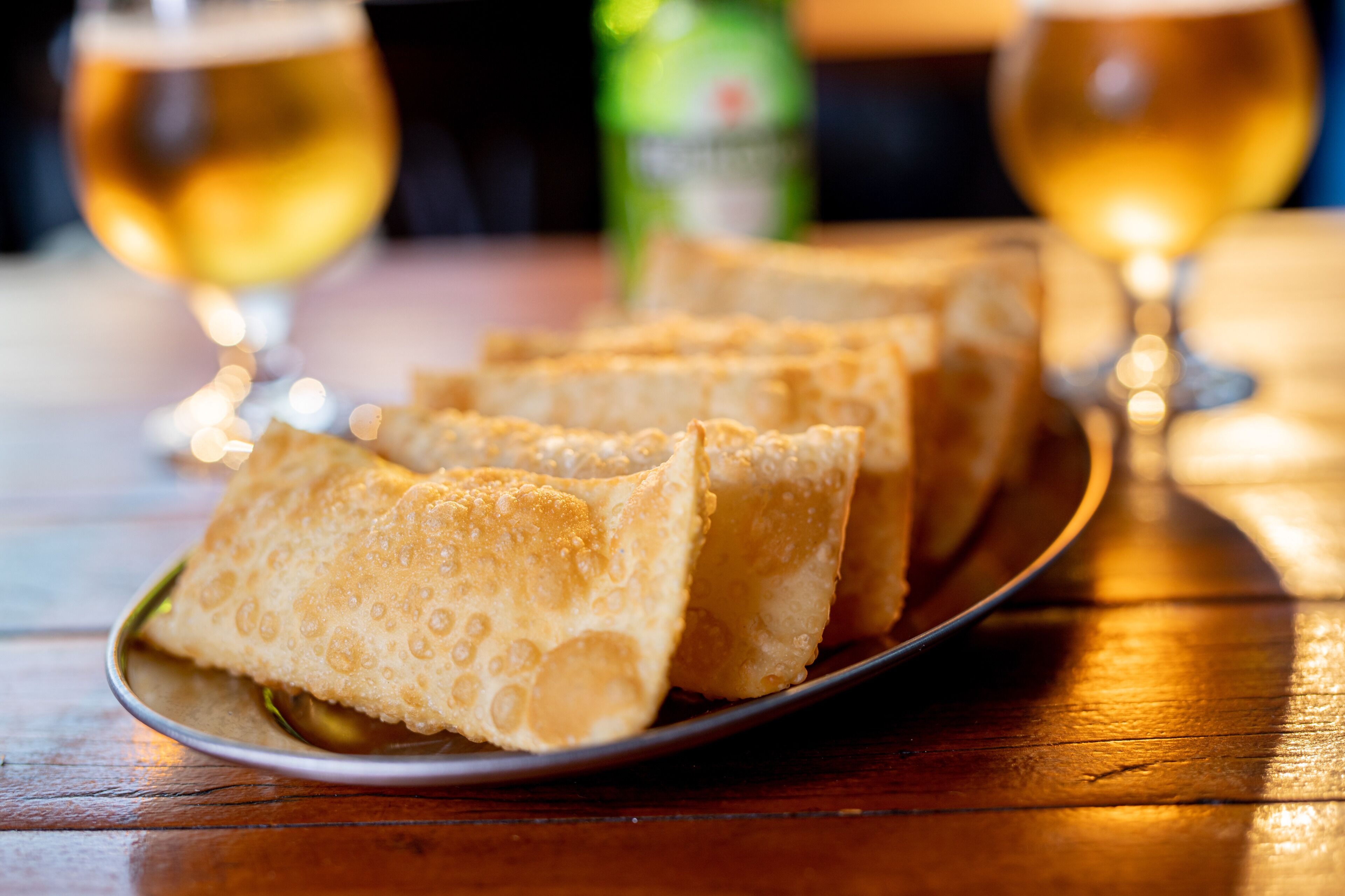 A plate of crispy, golden-brown fried items, possibly fritters, on a dark plate.