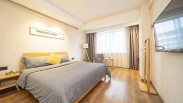 A hotel room with a large bed, a bedside table, a TV, and a window with curtains.