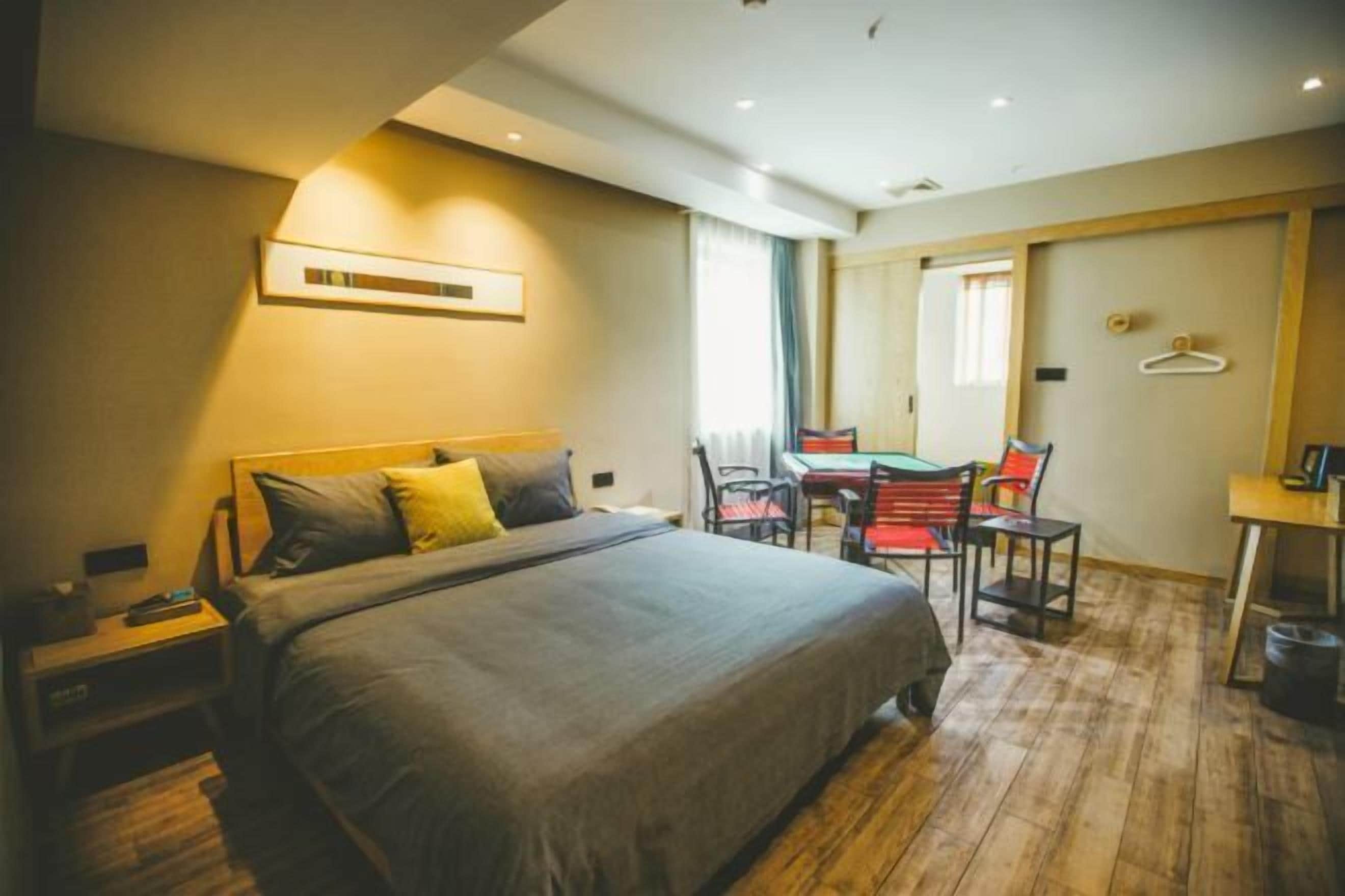 A hotel room with a large bed, a desk, and a chair.