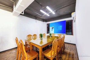 A conference room with a glass table, wooden chairs, and a blue screen on the wall. - Yueyang Meimei Su Hotel (Nanhu Square) (Yueyang)