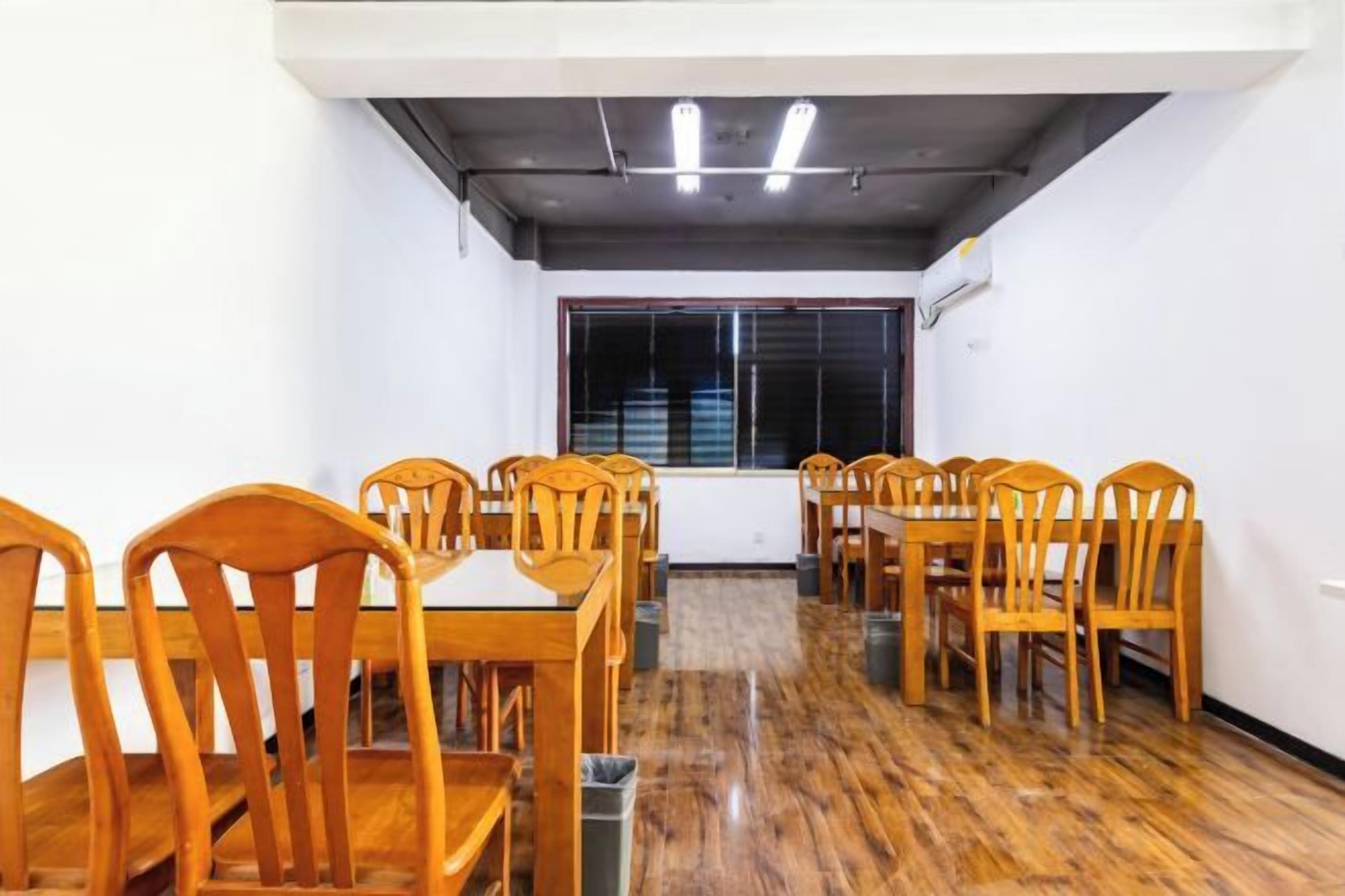 A conference room with wooden tables and chairs, a large window, and a modern ceiling design.