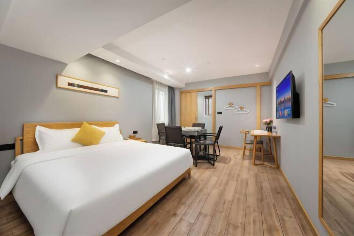 A modern hotel room with a large bed, a desk, and a television.