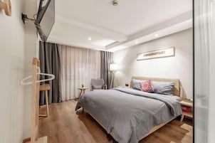 Una habitación de hotel moderna con una cama grande, un escritorio, una silla y un televisor montado en la pared.