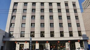 A multi-story hotel with a symmetrical facade, large windows, and a central entrance with a red lantern. - Huatian Hotel (Khorgas)
