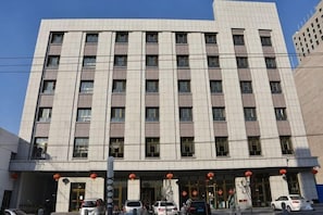 A multi-story hotel with a symmetrical facade, large windows, and a central entrance with a red lantern. - Huatian Hotel (Khorgas)