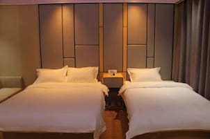 Habitación doble con dos camas, una mesita de noche entre ellas y un cabecero con diseño de panel vertical.