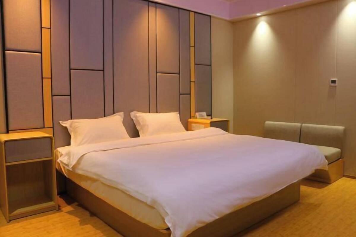 Una habitación de hotel moderna con una cama grande, una mesita de noche y un espacio para sentarse.