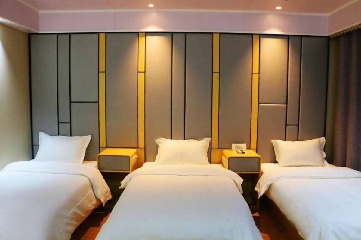 Habitación de hotel con dos camas, un amplio panel decorativo en la pared y lámparas de noche.