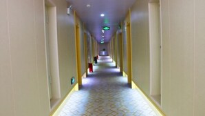 A long, narrow hotel corridor with patterned flooring and yellow pillars. - Huatian Hotel (Khorgas)