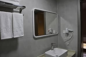 A bathroom with a sink, mirror, towel rack, and hairdryer. - Huatian Hotel (Khorgas)
