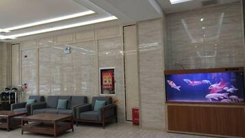A hotel lobby with a large aquarium, seating area, and a reception desk.